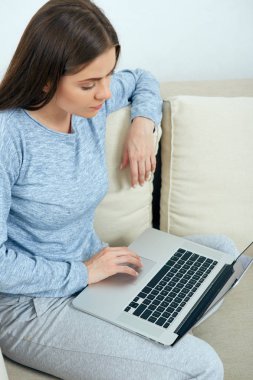 kanepede oturan ve evde laptop ile çalışan kadın 