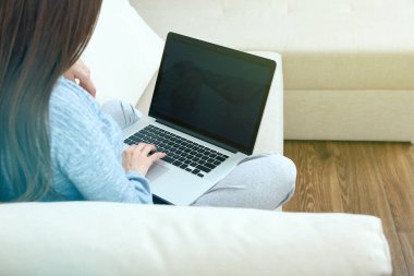 kanepede oturan ve evde laptop ile çalışan kadın 