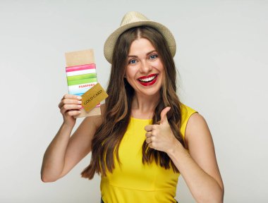 pasaport ve bilet ve kredi kartı tutan ve başparmak, seyahat kavramı gösterilen mutlu gülümseyen kadın 