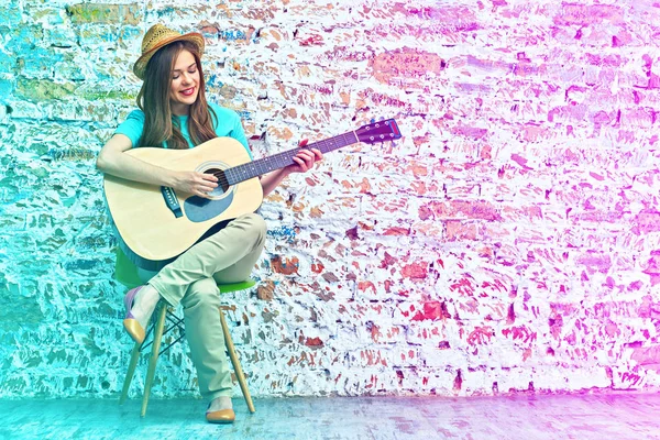 Jeune femme assise sur une chaise jouer de la guitare . — Photo