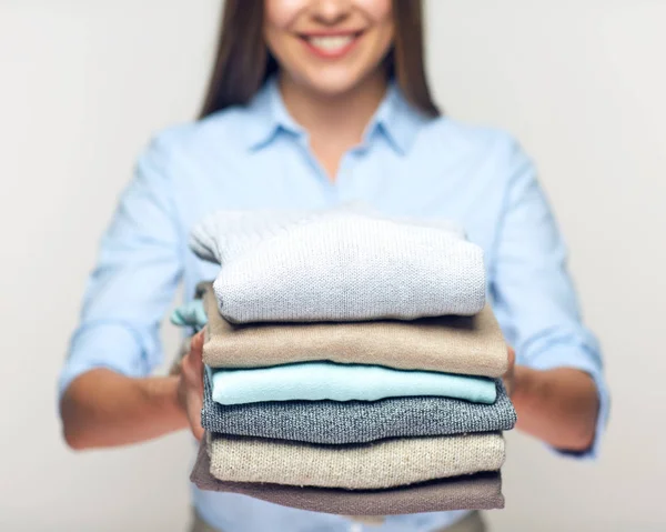 Woman holding stack of folded sweaters. — Stock Photo, Image