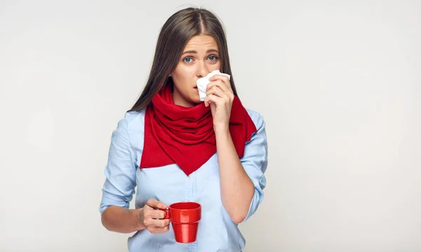 Хвороба жінка тримає червону чашку підірвати ніс в паперовій тканині . — стокове фото