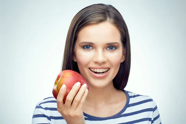 Chica sonriente con frenos dentales sosteniendo manzana roja . — Foto de Stock
