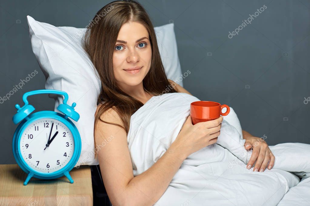 After awakening woman drinking  coffee under blanket, concept of best morning time 