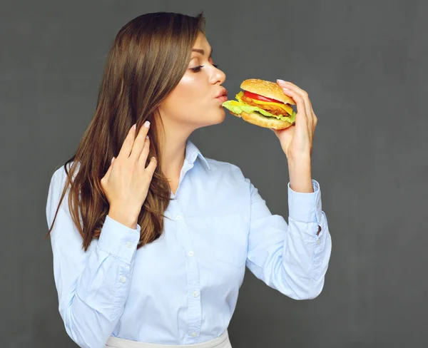 Młoda kobieta całuje burger. Szare ściany — Zdjęcie stockowe