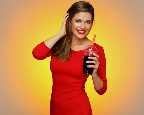 Mujer sonriente vistiendo vestido rojo sosteniendo bebida cola . — Foto de Stock