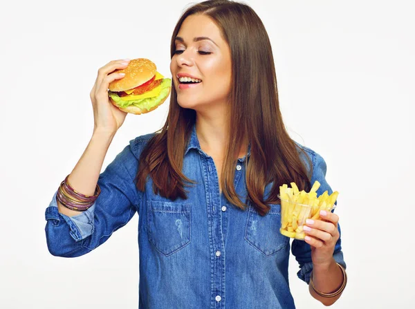 蓝色牛仔裤的微笑的妇女持有汉堡和法国薯条在白色背景下隔离 — 图库照片