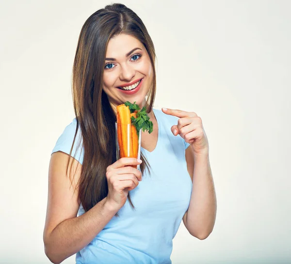 Sonriente chica sosteniendo vidrio con zanahoria y el dedo que apunta . — Foto de Stock