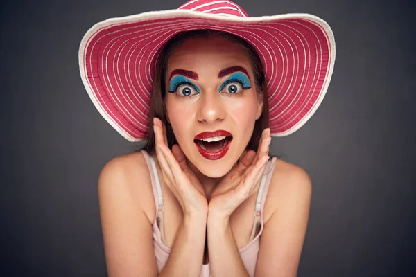 滑稽的面孔妇女佩带夏天海滩帽子与明亮的妆看照相机 — 图库照片