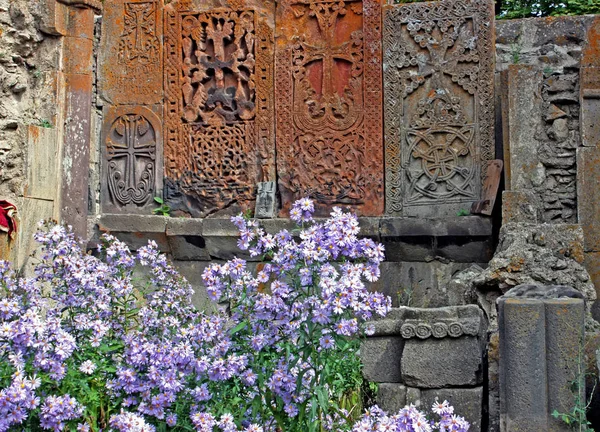 Lindas flores lilás no fundo da antiga cruz de pedra — Fotografia de Stock