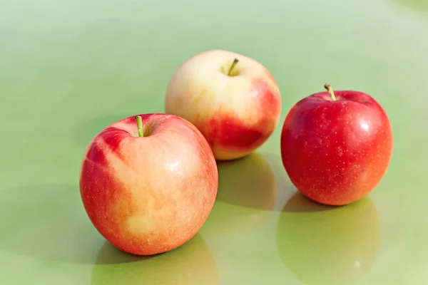 Röda äpplen på en grön bakgrund — Stockfoto