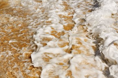 Sörf. Güzel kabartma köpük sarı kum üzerinde.