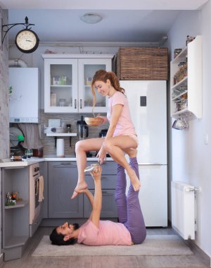 Genç çift evde farklı yerlerde akro yoga pozları vererek eğleniyor..