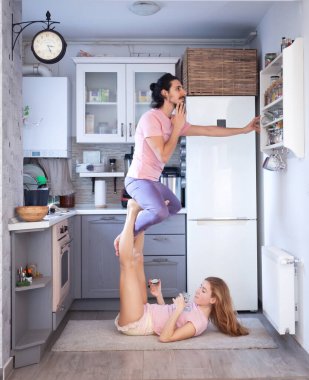 Genç çift evde farklı yerlerde akro yoga pozları vererek eğleniyor..