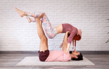 Genç çift evde farklı yerlerde akro yoga pozları vererek eğleniyor..