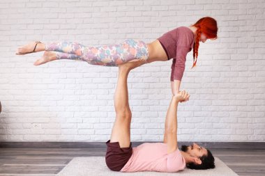 Genç çift evde farklı yerlerde akro yoga pozları vererek eğleniyor..