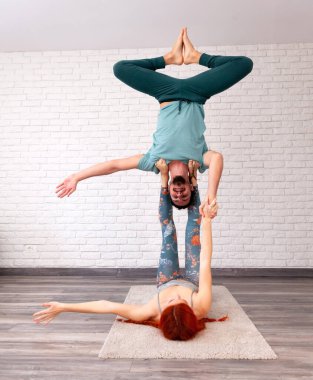 Genç çift evde farklı yerlerde akro yoga pozları vererek eğleniyor..