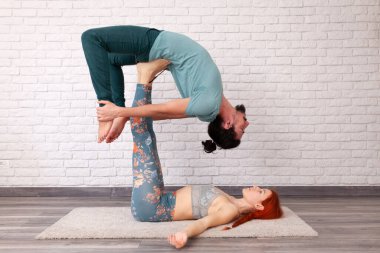 Genç çift evde farklı yerlerde akro yoga pozları vererek eğleniyor..
