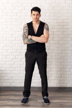 Vücudunda bir sürü dövmesi olan genç bir adamın ciddi portresi..