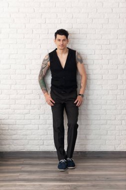 Vücudunda bir sürü dövmesi olan genç bir adamın ciddi portresi..