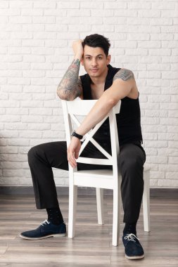 Vücudunda bir sürü dövmesi olan genç bir adamın ciddi portresi..