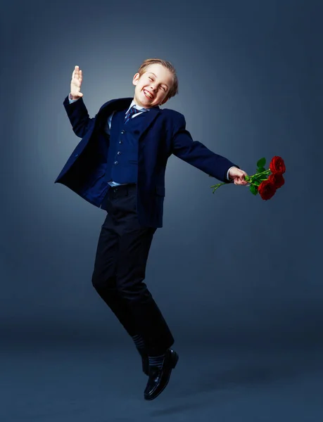Hansome chłopiec w czarnym garniturze z różami w ręce — Zdjęcie stockowe
