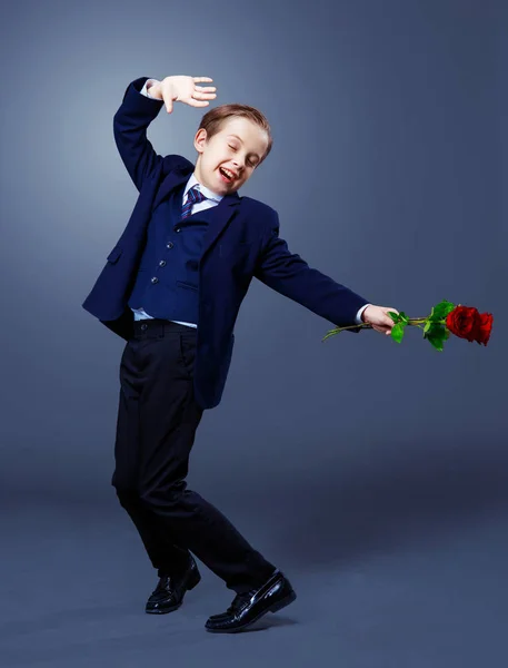 Hansome niño vistiendo un traje negro con rosas en las manos — Foto de Stock