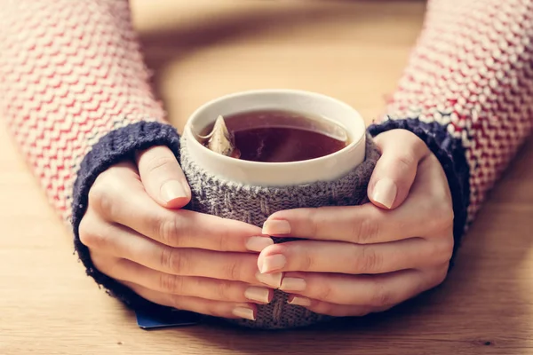 Tazza calda di tè riscaldare le mani della donna — Foto Stock