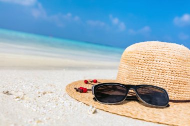 Sun hat and sunglasses on sand  clipart