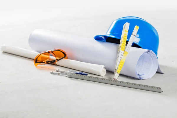 Hard hat with safety glasses and blueprints — Stock Photo, Image