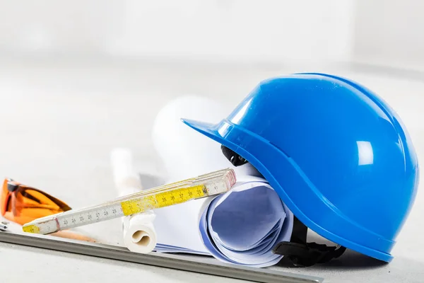 Hard hat with safety glasses and blueprints — Stock Photo, Image