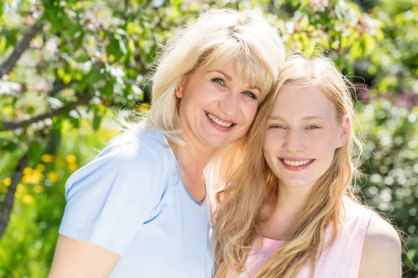 Mother and daughter hugging in summer garden — Stock Photo, Image