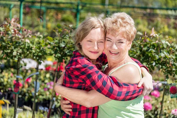Großmutter und Enkelin umarmen sich im Garten. — Stockfoto