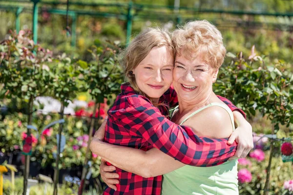 Babička a vnučka objímání v zahradě. — Stock fotografie