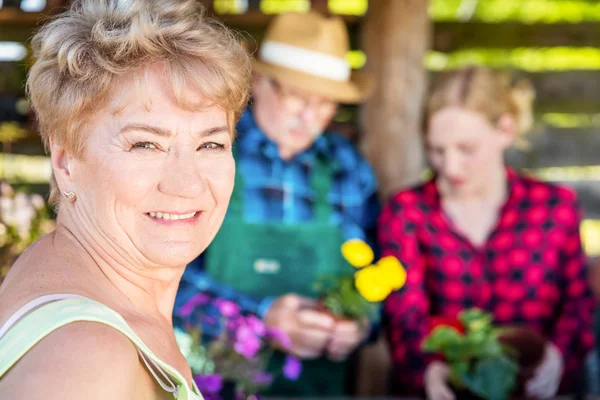 Grootmoeder op zoek naar de camera. Planten van bloemen met de familie. — Stockfoto