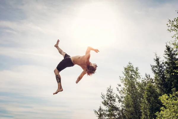 Jovem fazendo um backflip no ar . — Fotografia de Stock