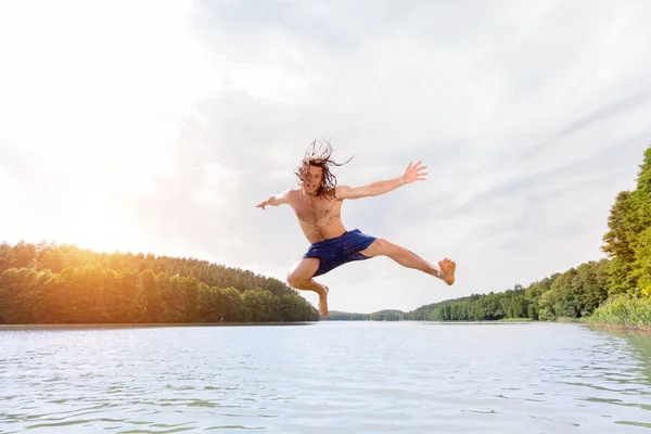 Jovem homem apto fazendo um salto em um lago . — Fotografia de Stock