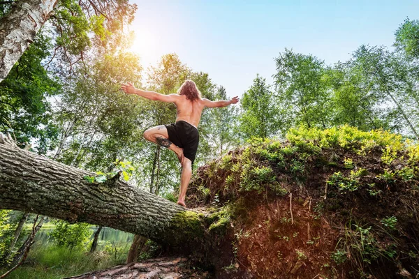 Jovem de pé em um tronco de árvore na floresta . — Fotografia de Stock