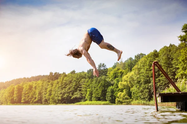 Młody zmieścić człowiek skoki do jeziora — Zdjęcie stockowe