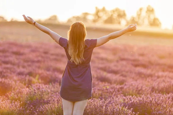 Счастливая молодая женщина на лавандовом поле на закате — стоковое фото