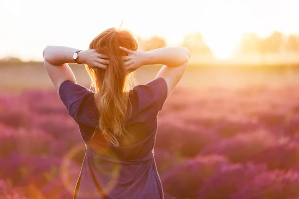 Young woman touching her long hair looking at lavender field — Stock Photo, Image