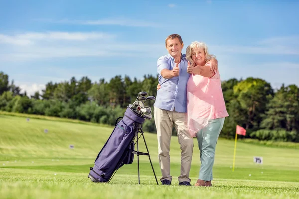 Casal sênior dando polegares em um campo de golfe . — Fotografia de Stock