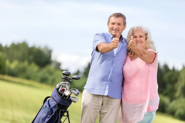 Pareja mayor mostrando signo OK en un campo de golf . — Foto de Stock