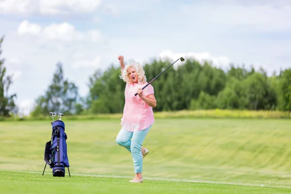 Mature woman jumping with success on a golf course. — Stock Photo, Image