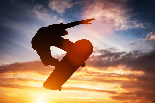 Skateboardista skákání při západu slunce. — Stock fotografie