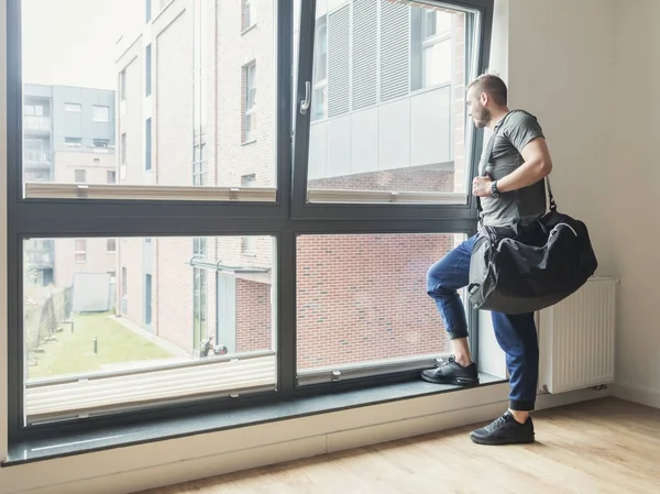 Fitter Junger Mann Mit Trainingstasche Der Durch Ein Fenster Blickt — Stockfoto