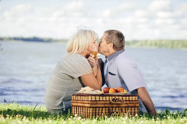 シニアのカップルが湖のほとりにキスします ピクニック 高齢者の幸せな結婚の概念 — ストック写真