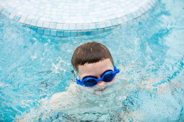 スイミング プールは水泳のゴーグルで水から浮上中の少年 — ストック写真