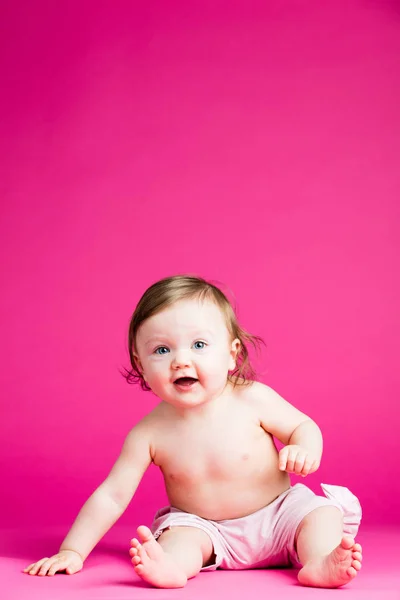 ピンクの背景の床に座っての幼児 — ストック写真