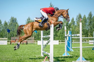Sürücü üzerinde kırmızı arka plan mavi gökyüzü üzerinde atlama için arenada üstesinden at yüksek engelleri Jumper'ı göster